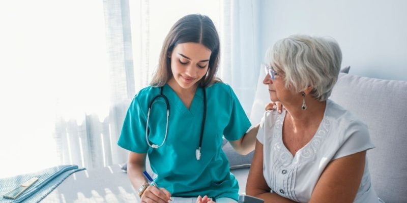 Nurse doing blood pressure monitoring for senior woman at home. Close up photo of blood pressure measurement. Nurse measuring blood pressure of senior woman at home. Smiling to each other.